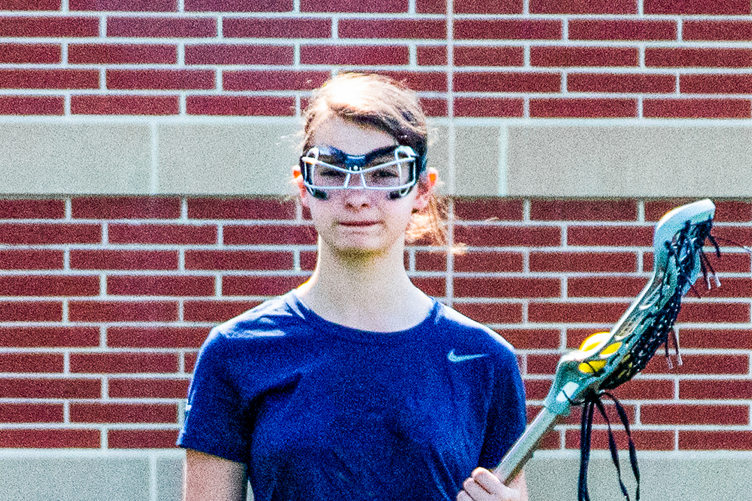 picture of a girls lacrosse player wearing eyewear while holding a stick